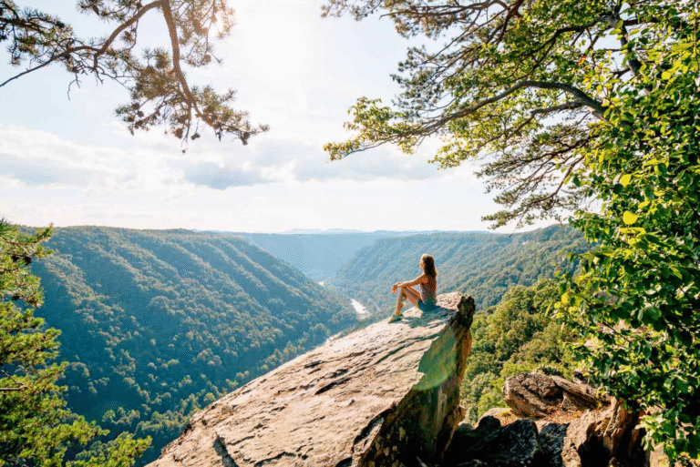 woman sitting on a rock overseeing a valley.